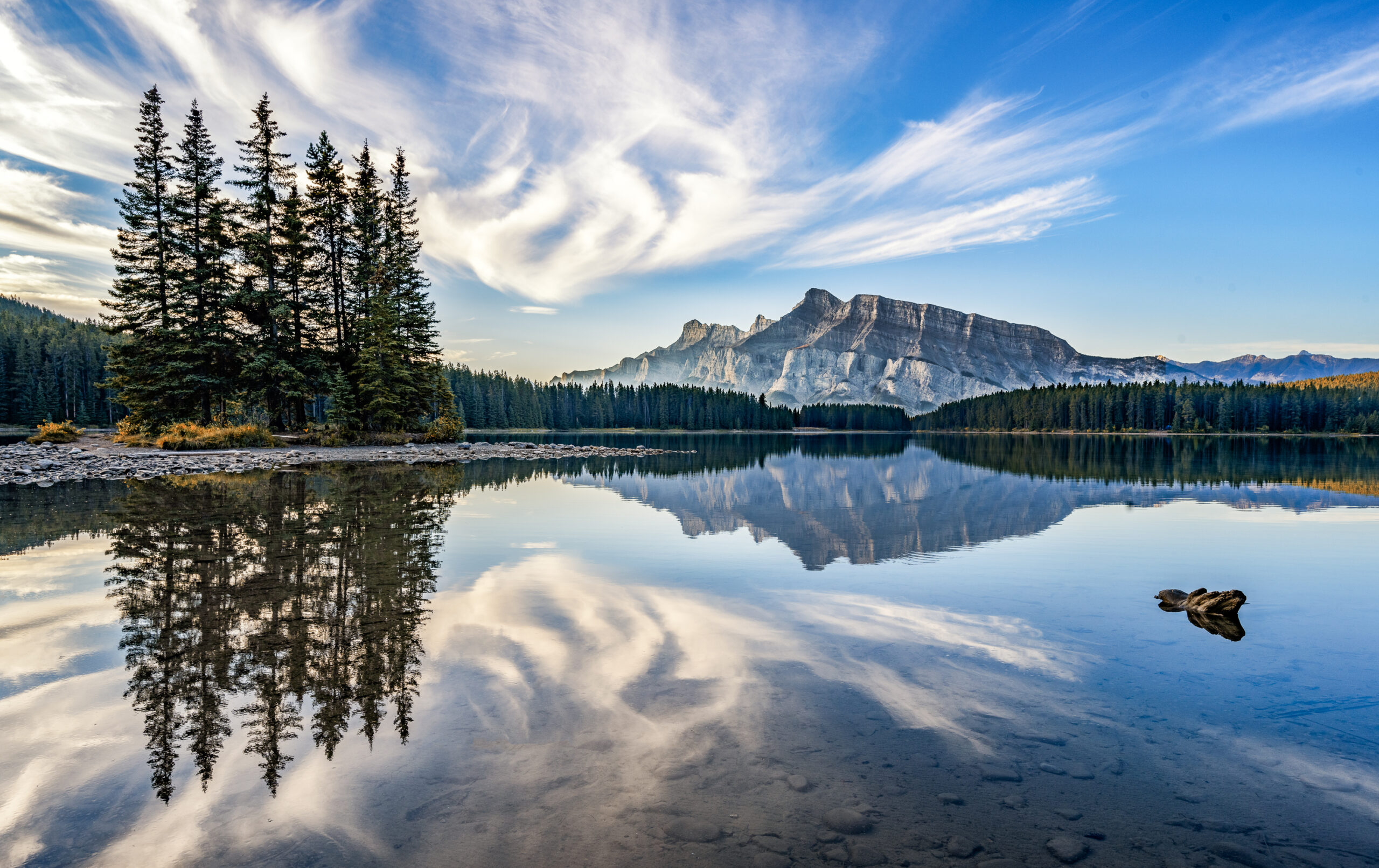 Two Jack Lake in het zachte ochtendlicht, met een opvallende wolkenformatie boven het berglandschap.